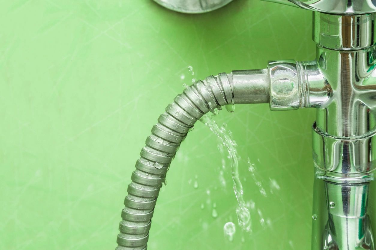 A close up of the water hose on a green wall